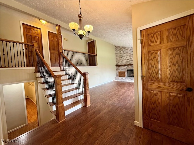 83 Oneida Trl, Malvern, OH 44644 - stairway featuring wood finished floors, an inviting chandelier, vaulted ceiling, a fireplace, and a textured ceiling