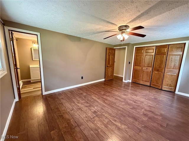 83 Oneida Trl, Malvern, OH 44644 - unfurnished bedroom with a textured ceiling, connected bathroom, ceiling fan, baseboards, and dark wood-style flooring