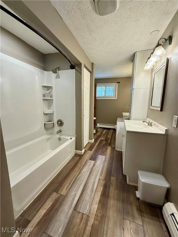 83 Oneida Trl, Malvern, OH 44644 - full bathroom with wood finished floors, a baseboard radiator, baseboard heating, shower / bathtub combination, and vanity