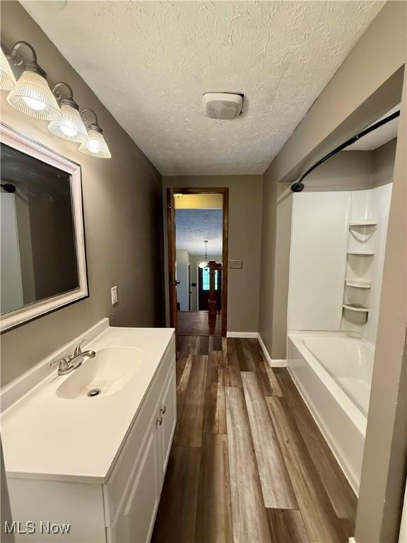 83 Oneida Trl, Malvern, OH 44644 - bathroom featuring a textured ceiling, baseboards, wood finished floors, vanity, and bathtub / shower combination
