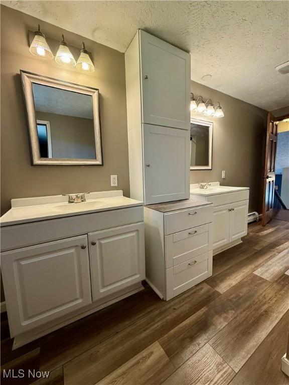 83 Oneida Trl, Malvern, OH 44644 - full bathroom featuring wood finished floors, two vanities, a textured ceiling, and a sink