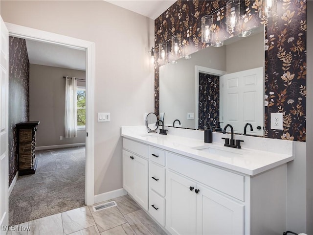 full bath featuring double vanity, visible vents, baseboards, and a sink