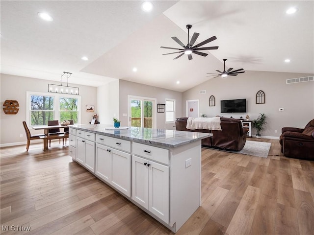 kitchen featuring light wood finished floors, ceiling fan, a center island, visible vents, and white cabinets