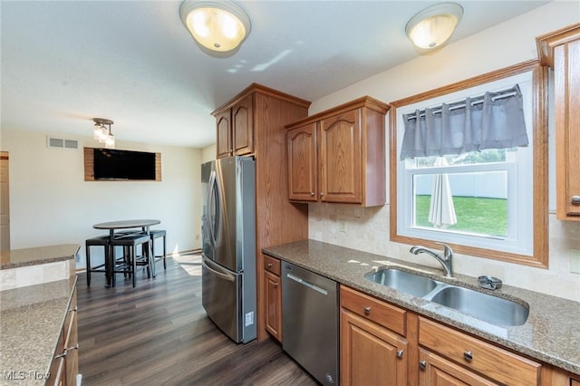 kitchen featuring a sink, brown cabinets, stainless steel appliances, and dark wood-style flooring