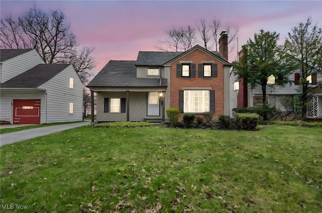 traditional-style house featuring a lawn, an attached garage, and a chimney