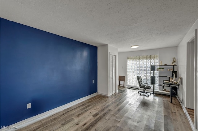 office featuring a textured ceiling, wood finished floors, and baseboards