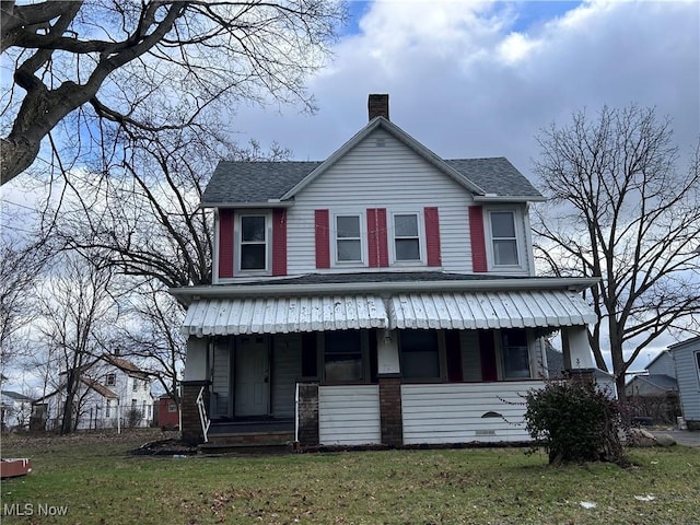 view of front of house featuring a chimney, roof with shingles, covered porch, a front yard, and brick siding