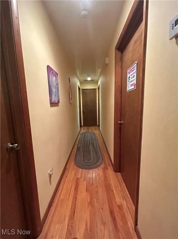 hall featuring baseboards and light wood-style flooring
