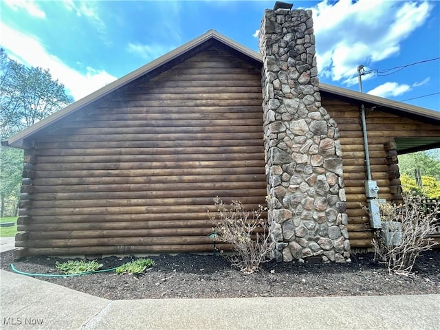 view of home's exterior featuring a chimney and log siding