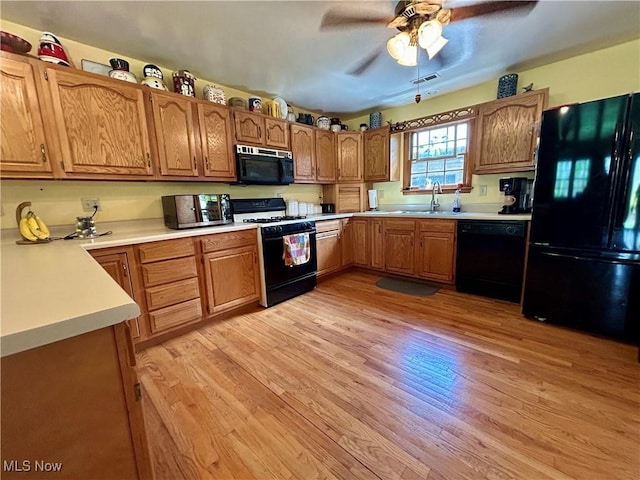kitchen with visible vents, a sink, light countertops, black appliances, and light wood-style flooring