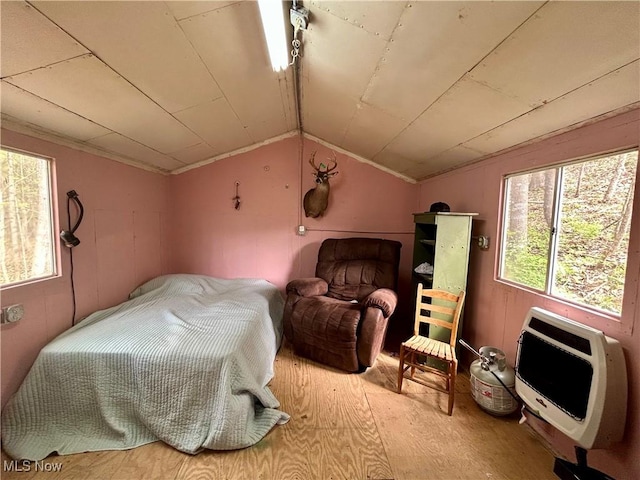 bedroom with heating unit, wood finished floors, and lofted ceiling