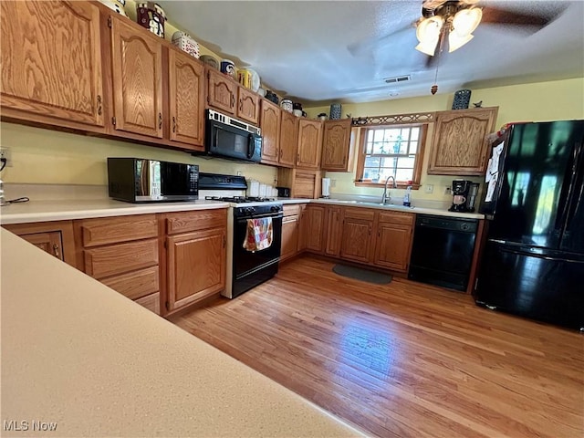 kitchen featuring visible vents, ceiling fan, light countertops, light wood-style flooring, and black appliances