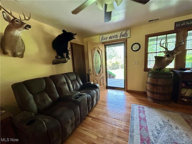 living room featuring visible vents, a ceiling fan, baseboards, and light wood-type flooring
