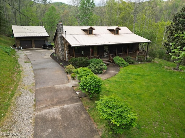 view of front of property featuring covered porch, a forest view, a front lawn, and a garage