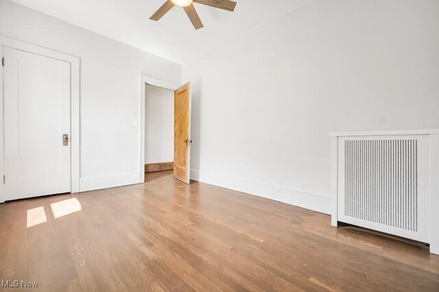 1357 E Blvd Unit 2, Cleveland, OH 44106 - unfurnished bedroom featuring baseboards, radiator, a ceiling fan, and wood finished floors