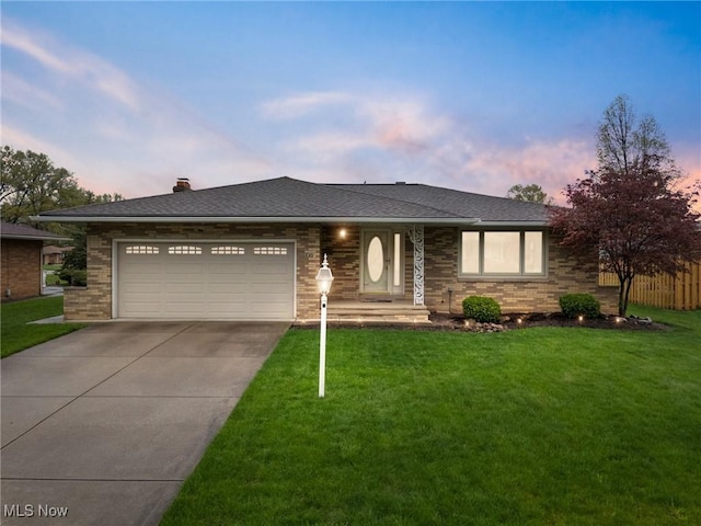 view of front of house featuring concrete driveway, a garage, a front lawn, and brick siding