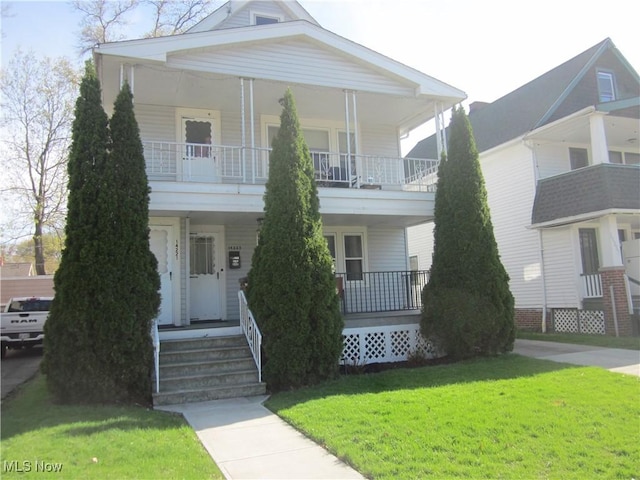 greek revival inspired property featuring a porch, a front lawn, and a balcony