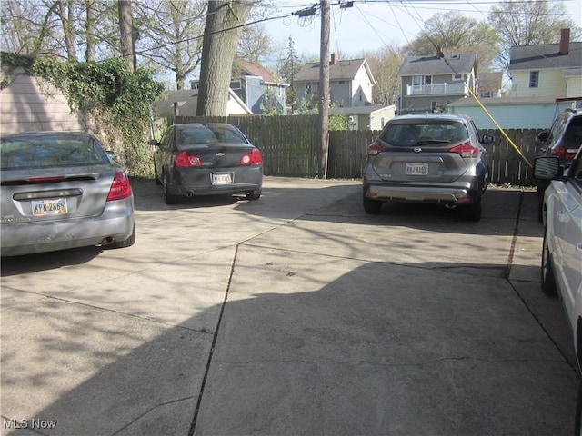 uncovered parking lot with a residential view and fence