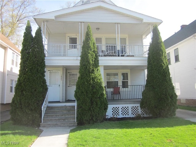 view of front of property featuring covered porch, a front lawn, and a balcony