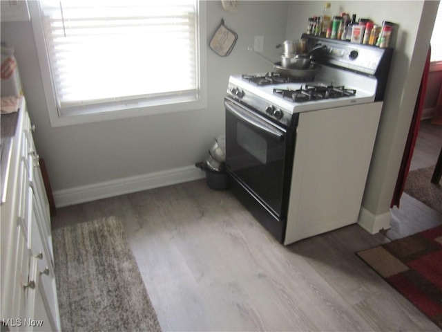 kitchen with white cabinetry, white gas stove, light wood-style flooring, and baseboards