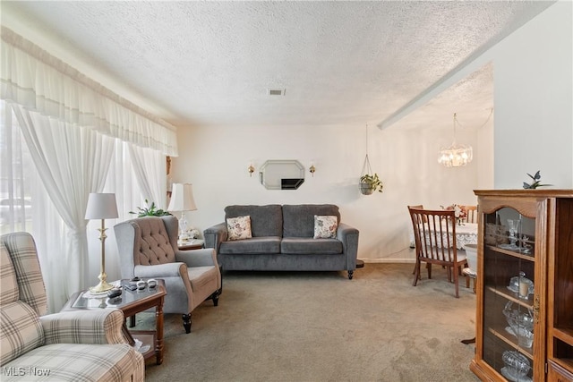 carpeted living area featuring a chandelier, visible vents, and a textured ceiling