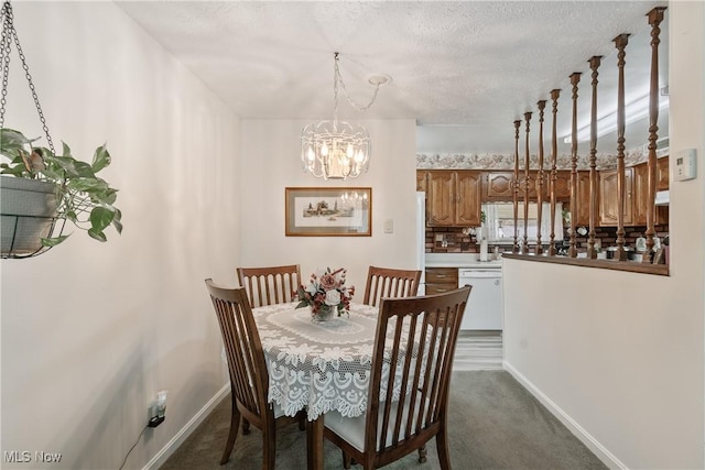 dining room featuring dark carpet, a textured ceiling, a notable chandelier, and baseboards