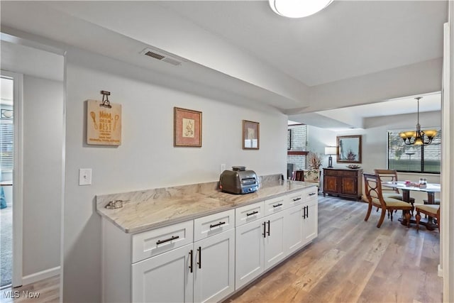bar featuring a wealth of natural light, visible vents, light wood-type flooring, and a notable chandelier