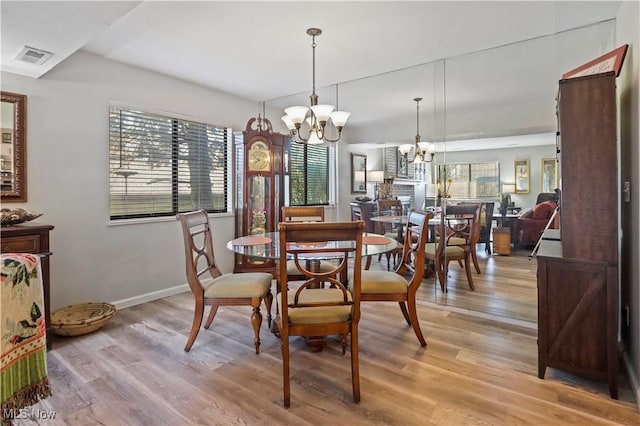 dining room with light wood finished floors, visible vents, a chandelier, and baseboards