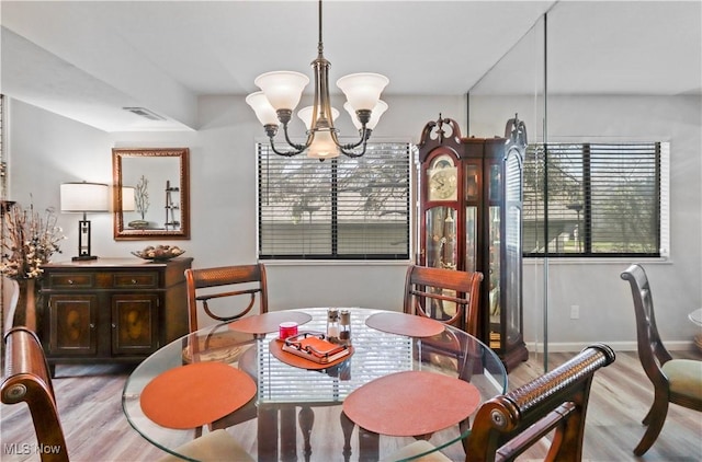 dining room with baseboards, visible vents, wood finished floors, and an inviting chandelier