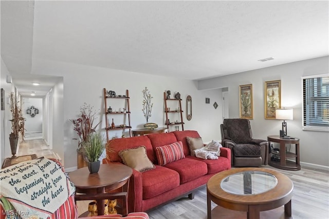 living area featuring visible vents, light wood finished floors, and baseboards