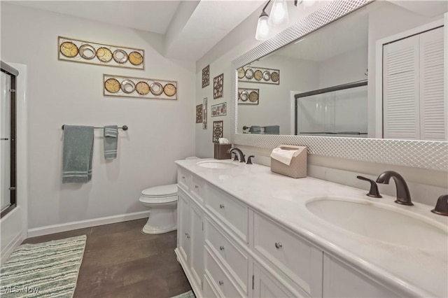 full bath featuring toilet, baseboards, a shower with door, and a sink