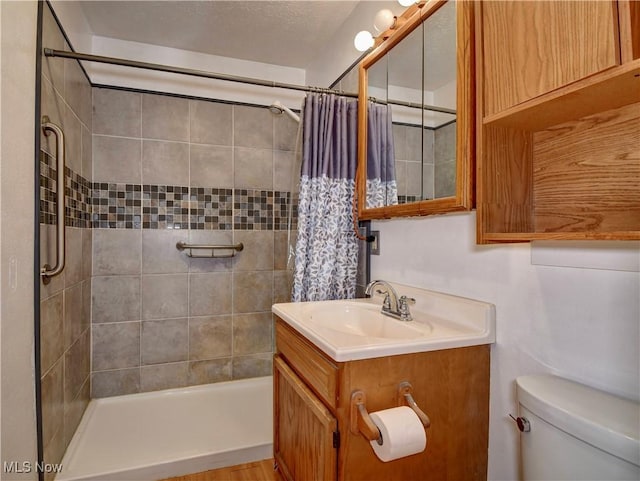 full bathroom featuring a tile shower, toilet, and vanity