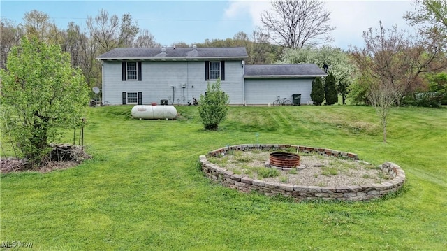 rear view of property featuring a fire pit and a lawn