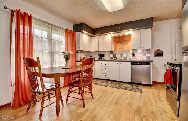 kitchen with white cabinetry, light wood-style floors, a textured ceiling, and appliances with stainless steel finishes