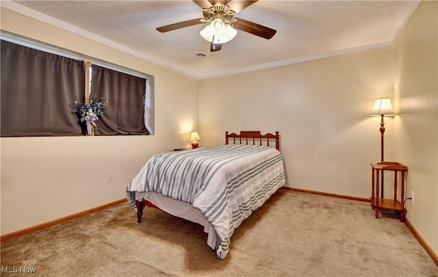 carpeted bedroom with baseboards, visible vents, ornamental molding, and ceiling fan