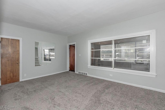 carpeted empty room featuring baseboards and visible vents