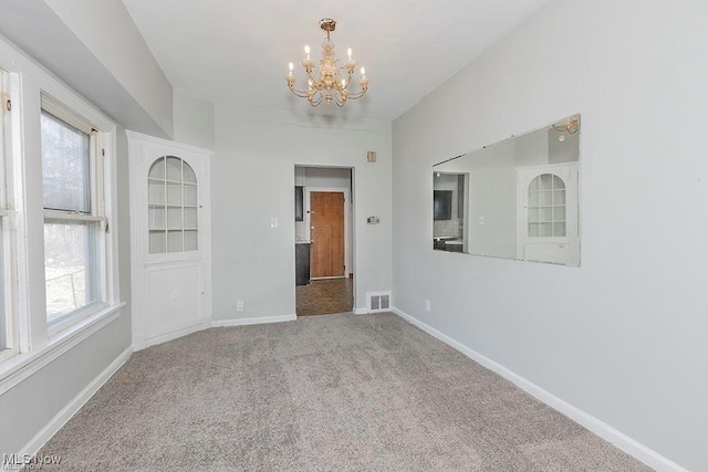 unfurnished room featuring visible vents, baseboards, a chandelier, and carpet floors