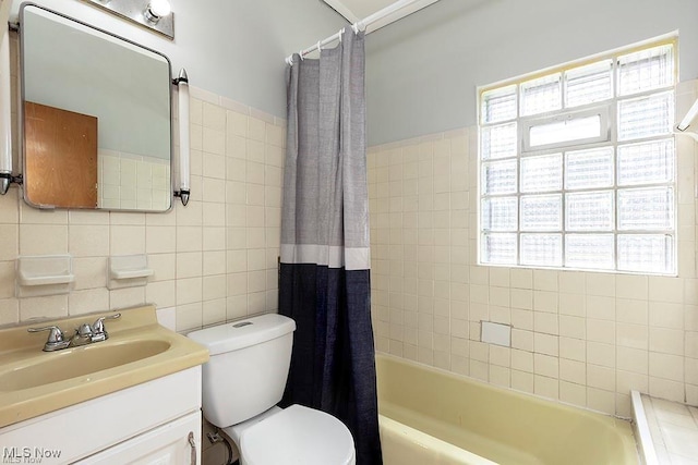 full bathroom with tile walls, shower / bathtub combination with curtain, toilet, and vanity