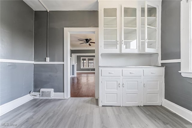 interior space with wood finished floors, ceiling fan, visible vents, and baseboards