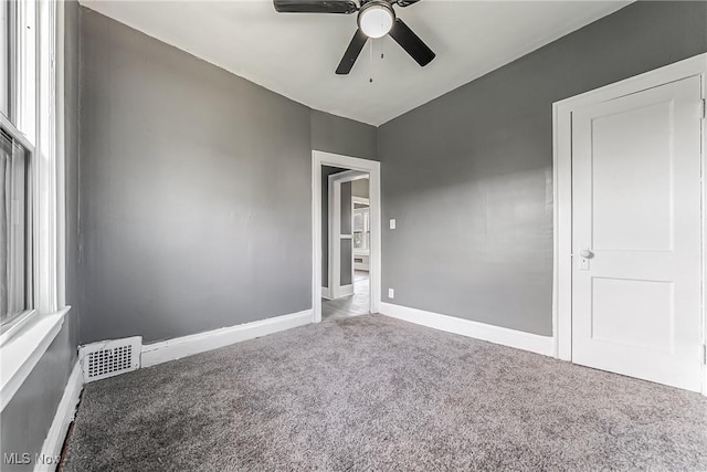 carpeted spare room featuring a ceiling fan, visible vents, and baseboards