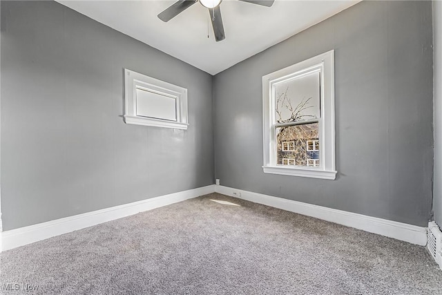 carpeted empty room with a ceiling fan and baseboards