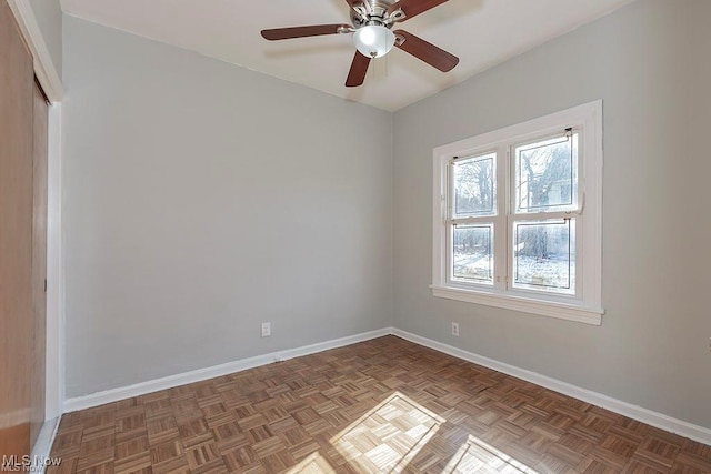 spare room featuring ceiling fan and baseboards
