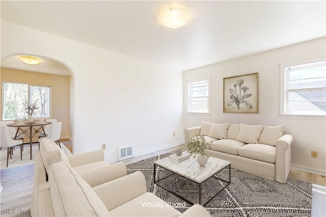 living area with visible vents, plenty of natural light, and arched walkways
