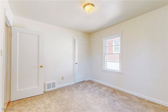 empty room featuring baseboards, visible vents, and light colored carpet