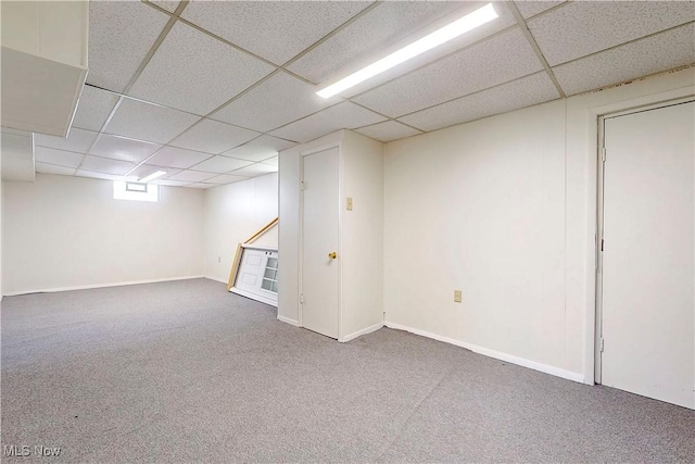 basement featuring baseboards, carpet, and a paneled ceiling