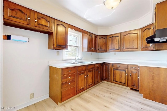 kitchen featuring light countertops, brown cabinets, light wood-style flooring, and a sink