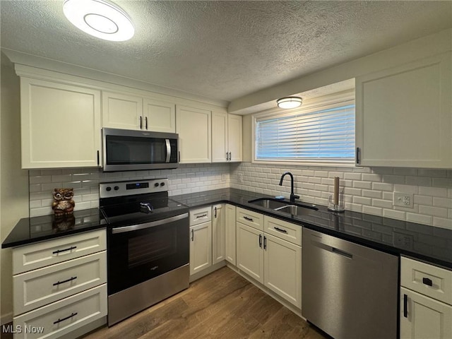 kitchen with a textured ceiling, stainless steel appliances, dark wood-style floors, and a sink