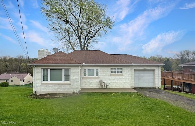 back of house featuring a lawn, driveway, stone siding, a chimney, and an attached garage