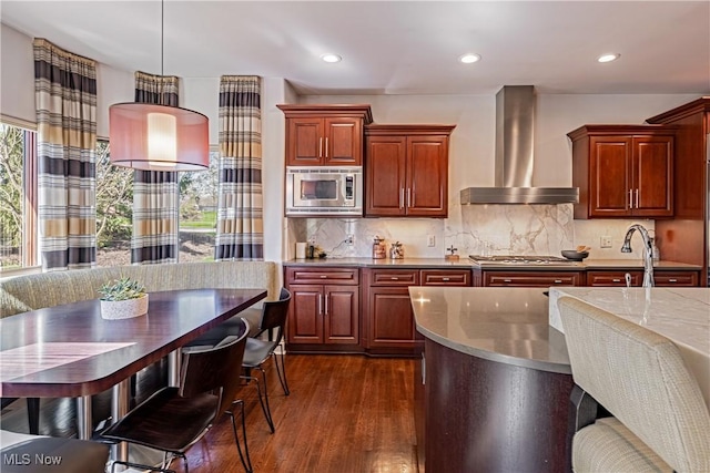 3601 Chapelton Ct, Richfield, OH 44286 - kitchen featuring wall chimney range hood, appliances with stainless steel finishes, dark wood finished floors, tasteful backsplash, and decorative light fixtures