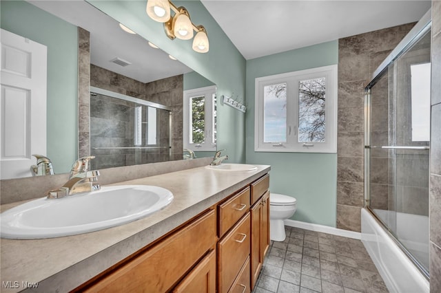 bathroom with a sink, baseboards, toilet, and double vanity